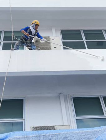 Rope access painter applying external finish on building facade